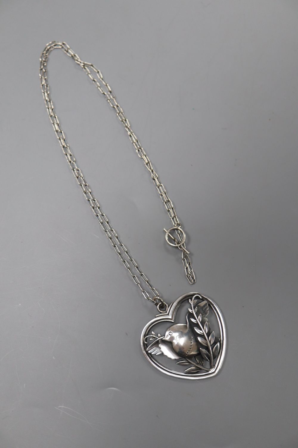 A George Jensen sterling Robin & fearn heart shaped pendant, with white metal necklace, no. 97, 41mm, gross 15.6 grams.